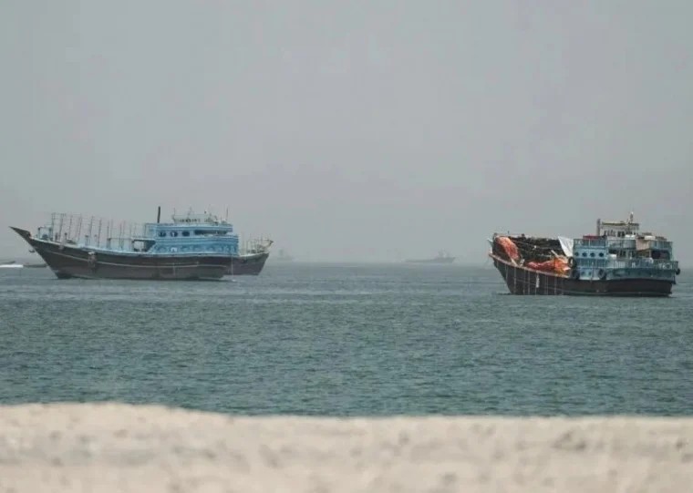 Dois navios cargueiros no mar em dia nublado, com o primeiro à esquerda e o segundo à direita, vistos a certa distância sobre as águas tranquilas.