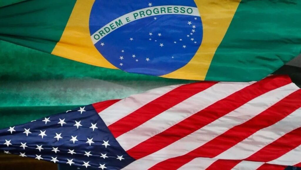 Bandeiras do Brasil e dos Estados Unidos entrelaçadas ao vento, com o brasão e as estrelas visíveis, transmitindo parceria e integração entre os países.