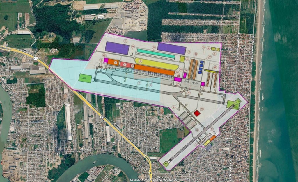 Imagem aérea com mapa do complexo industrial em área urbana e às margens do rio, destacando pátios e pavilhões com cores diferenciadas e vias internas demarcadas.