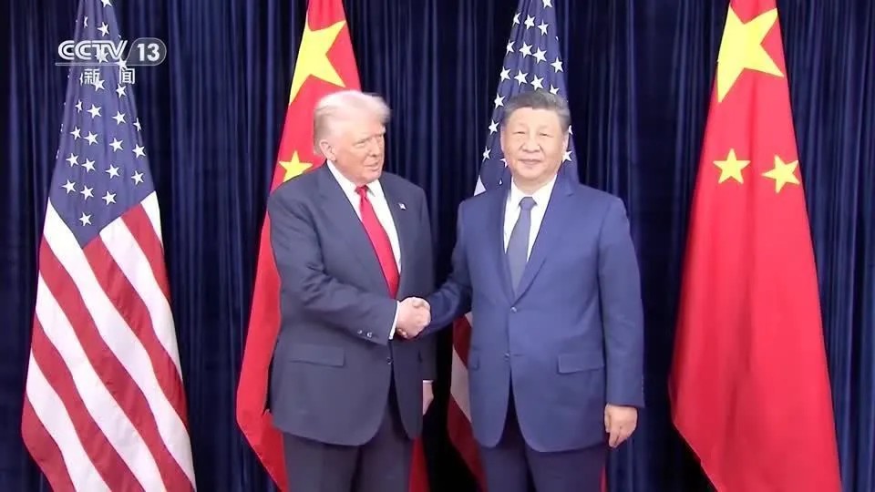 Encontro entre Donald Trump e Xi Jinping em cerimônia com bandeiras dos Estados Unidos, China e demais países ao fundo, em imagem de transmissão.