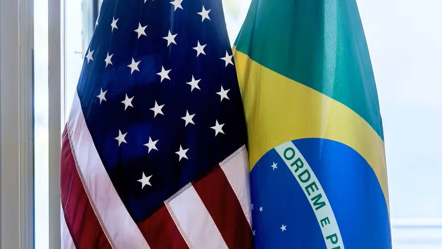 Bandeiras dos Estados Unidos e do Brasil lado a lado, com estrelas na bandeira americana e o brasão e a faixa azul e amarela na bandeira brasileira